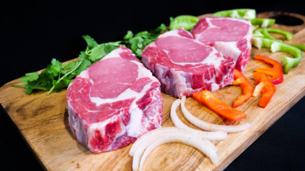 New york steaks with onions and bell peppers on display